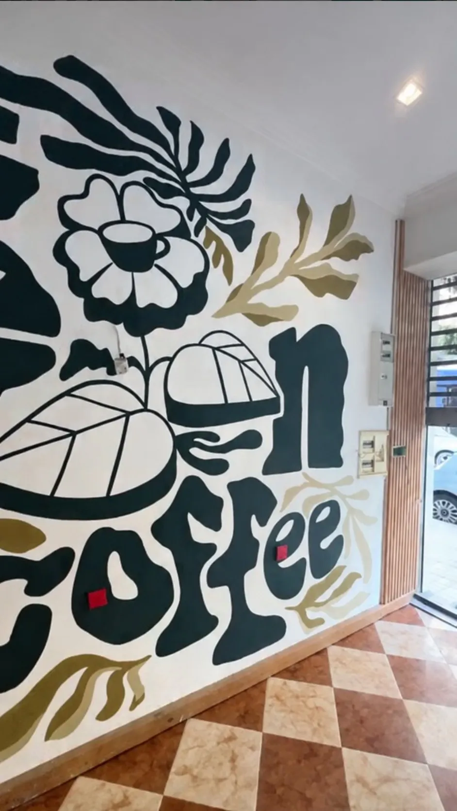 Détail de la fresque murale avec motifs floraux et tasse de café